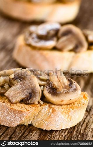 Fresh homemade mushroom and garlic bruschetta traditional Italian antipasto, photographed on rustic wood  Selective Focus, Focus on the left mushroom slice in the front . Fresh Mushroom Bruschetta