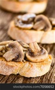 Fresh homemade mushroom and garlic bruschetta traditional Italian antipasto, photographed on rustic wood  Selective Focus, Focus on the left mushroom slice in the front . Fresh Mushroom Bruschetta
