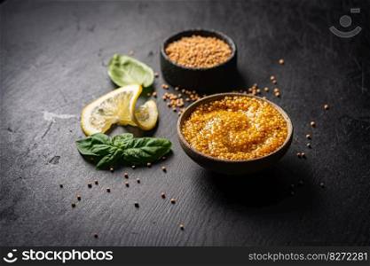 Fresh homemade organic dijon mustard in a bowl on black background, close up. Fresh organic mustard