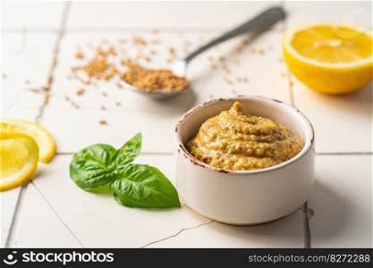 Fresh homemade organic dijon mustard in a bowl on white background, close up. Fresh organic mustard