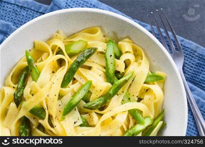Fresh homemade pasta dish of fettuccine or tagliatelle, green asparagus, garlic and lemon juice in bowl, ground black pepper on the top, photographed overhead (Selective Focus, Focus on the top of the dish). Fettuccine with Green Asparagus, Garlic and Lemon
