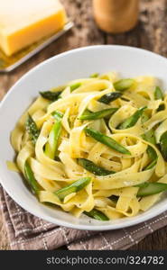 Fresh homemade pasta dish of fettuccine or tagliatelle, green asparagus, garlic and lemon juice in bowl, ground black pepper on top (Selective Focus, Focus one third into the dish). Fettuccine with Green Asparagus, Garlic and Lemon