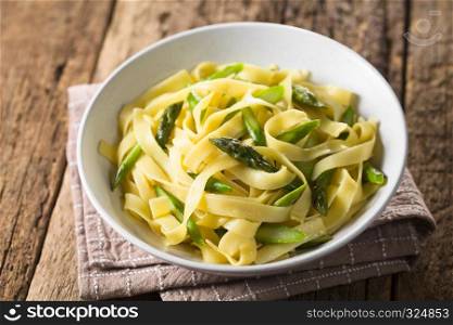 Fresh homemade pasta dish of fettuccine or tagliatelle, green asparagus, garlic and lemon juice in bowl (Selective Focus, Focus on the asparagus head in the middle). Fettuccine with Green Asparagus, Garlic and Lemon