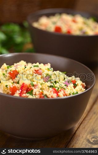 Fresh homemade Tabbouleh, an Arabian vegetarian salad made of couscous, tomato, cucumber, onion, garlic, parsley and lemon juice served in brown bowls on dark wood (Selective Focus, Focus one third into the tabbouleh). Fresh Homemade Tabbouleh, an Arabian Salad with Couscous