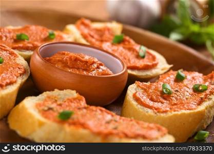 Fresh homemade tomato-butter spread in small bowl with canapes on wooden plate (Selective Focus, Focus on the middle of the spread in the bowl)