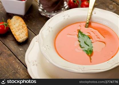 fresh homemade tomato soup with bay leaf on wooden table