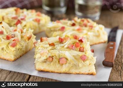 Fresh homemade traditional German Zwiebelkuchen onion cake, a savory baked pastry or pie made of yeast dough topped with onion, bacon, eggs and cream (Selective Focus, Focus in the middle of the first cake piece). German Zwiebelkuchen Onion Cake