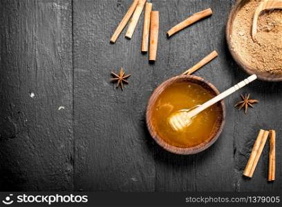 Fresh honey and ground cinnamon in a bowl. On a black wooden table.. Fresh honey and ground cinnamon in a bowl.