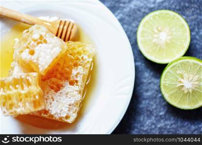 Fresh honey and lemon lime / Close up of yellow sweet honeycomb slice on white plate natural healthy food