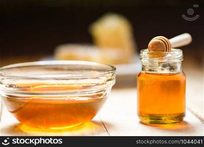 Fresh honey healthy food / Close up of yellow sweet honey in bowl and jar glass with wooden dipper on dark background - copy space