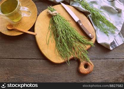 Fresh horsetail plant on a table with herbal tea on the wooden background .. Fresh horsetail plant on a table with herbal tea on the wooden background