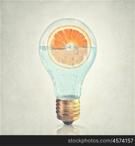 Fresh idea. Glass lightbulb filled with water and half of orange fruit