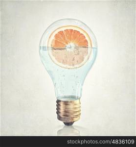 Fresh idea. Glass lightbulb filled with water and half of orange fruit
