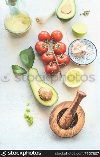 Fresh ingredients : avocado, tomatoes, lemon , garlic and olives oil for tasty salad making, top view. Healthy food. Vegetarian lunch or snack
