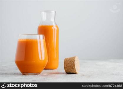 Fresh juice made of carrot filled in bottle and glass, cork near, isolated on white background, empty space. Detox drink. Healthy beverage