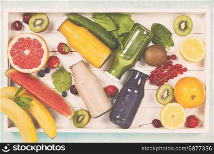 Fresh juices or smoothies with fruits and vegetables in wooden tray on blue background, top view, selective focus. Detox, dieting, clean eating, vegetarian, vegan, fitness, healthy lifestyle concept