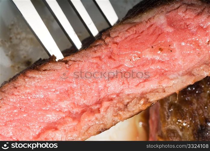 fresh juicy beef ribeye steak sliced ,with fork ove a plate