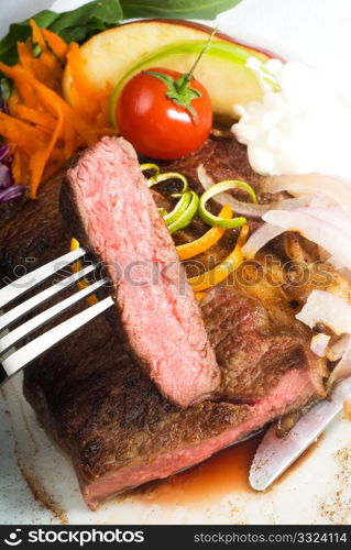 fresh juicy beef ribeye steak sliced ,with lemon and orange peel on top and vegetable beside