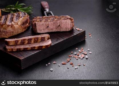 Fresh juicy delicious beef steak on a dark background. Meat dish with spices and herbs. Fresh juicy delicious beef steak on a dark background