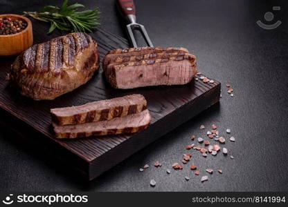 Fresh juicy delicious beef steak on a dark background. Meat dish with spices and herbs. Fresh juicy delicious beef steak on a dark background