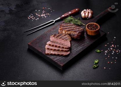 Fresh juicy delicious beef steak on a dark background. Meat dish with spices and herbs. Fresh juicy delicious beef steak on a dark background