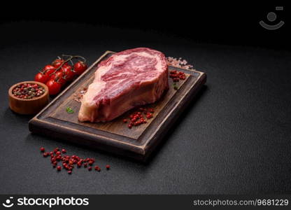 Fresh juicy raw beef striploin steak with salt and spices on a dark concrete background