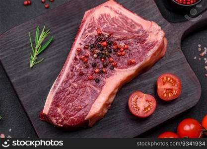 Fresh juicy raw new york beef steak with salt, spices and herbs on dark concrete background
