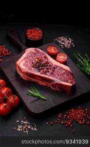 Fresh juicy raw new york beef steak with salt, spices and herbs on dark concrete background