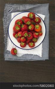 Fresh juicy strawberries on vintage enamelware on rustic background