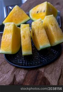 Fresh juicy yellow watermelon cut into triangles on old wooden table at balcony with city view. Tropical fruits. Copy space, Select focus.