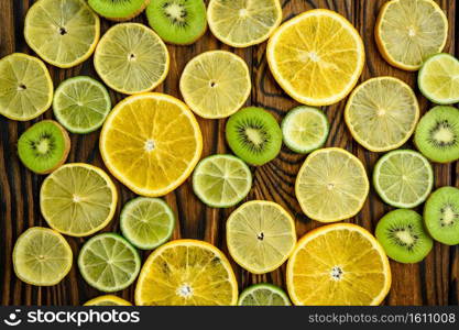 Fresh kiwi and lemon slices on wooden background, top view. Organic vegetarian food, grocery assortment, natural eco products, healthy lifestyle concept. Fresh kiwi and lemon slices on yellow background