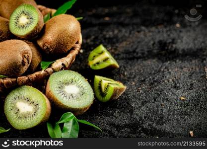 Fresh kiwi with leaves in a basket. On a black background. High quality photo. Fresh kiwi with leaves in a basket.