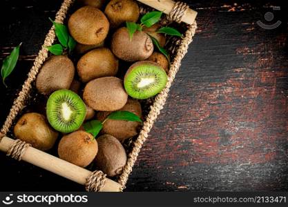 Fresh kiwi with leaves in a basket. On a rustic dark background. High quality photo. Fresh kiwi with leaves in a basket.