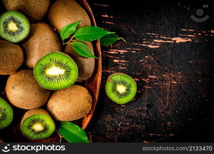 Fresh kiwi with leaves on a wooden plate. Against a dark background. High quality photo. Fresh kiwi with leaves on a wooden plate.