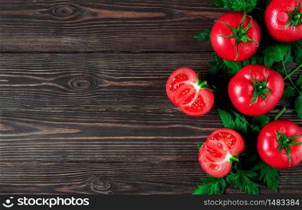 Fresh large whole tomatoes and cut in half are arranged on a dark wooden background. Ripe tomatoes in droplets of water. Copy space for text, layout.