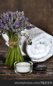 Fresh lavender flowers, zen stones, essential oil, candle and towel over wooden surface