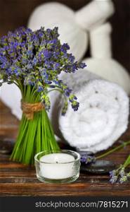 Fresh lavender flowers, zen stones,Herbal massage balls , candle and towel over wooden surface