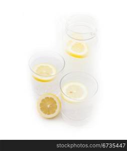 fresh lemonade drink with lemon slice closeup and pitcher carafe isolated