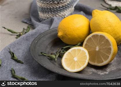 Fresh lemons and lemons leaves on rustic plate. Fresh citrus fruit background.