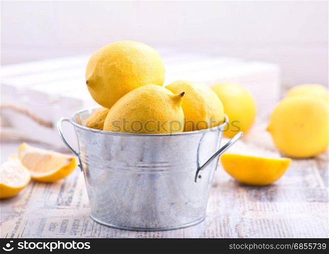 fresh lemons in metal bowl and on a table