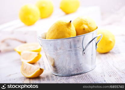 fresh lemons in metal bowl and on a table