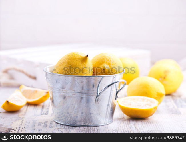 fresh lemons in metal bowl and on a table