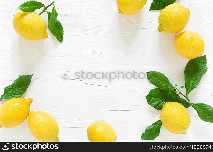 Fresh lemons with leaves on white wooden background, summer lemonade ingredient, vitamin c concept, top view