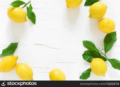 Fresh lemons with leaves on white wooden background, summer lemonade ingredient, vitamin c concept, top view