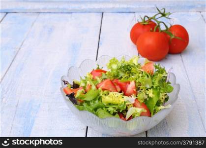 Fresh lettuce and tomato salad on kitchen table.