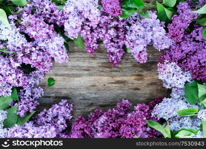 Fresh lilac flowers frame over wooden background with copy space, flat lay floral composition. Fresh lilac flowers