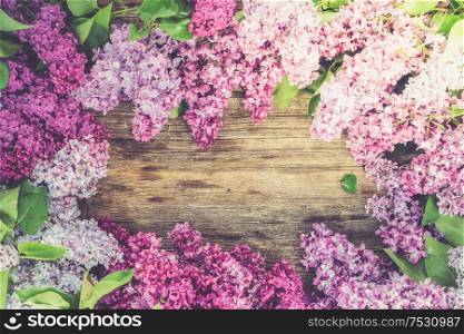 Fresh lilac flowers frame over wooden background with copy space, flat lay floral composition, toned. Fresh lilac flowers