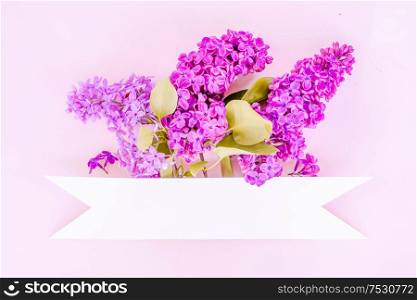 Fresh lilac flowers over pink background with copy space, flat lay floral composition with copy space, toned. Fresh lilac flowers
