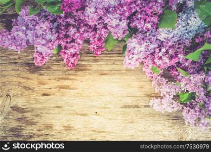 Fresh lilac flowers over wooden background with copy space, flat lay floral composition with copy space, toned. Fresh lilac flowers