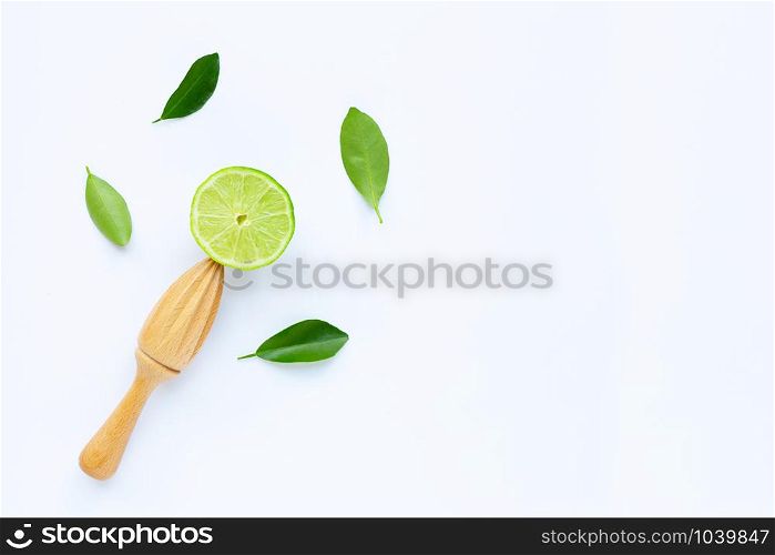 Fresh lime with wooden juicer on white background. Copy space
